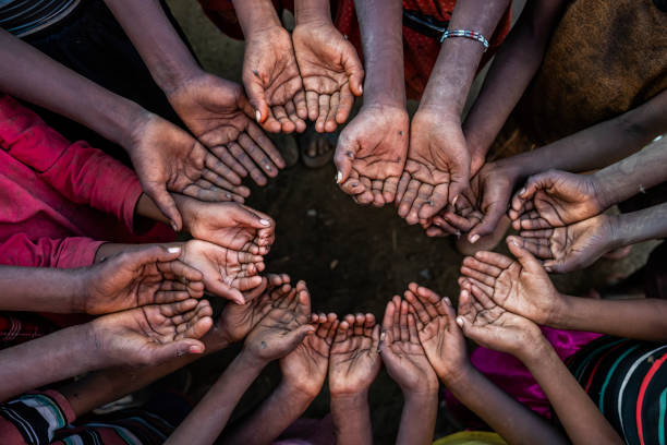 Poor African children keeping their hands up - asking for food. Many African children suffer from poverty - 20% of Africa’s children will die before the age of five.  Every day 30,000 children die from a combination of disease- infested water and malnutrition.